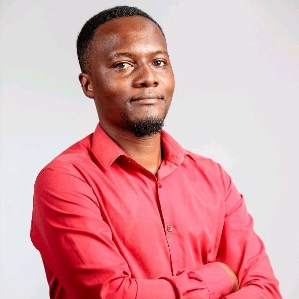 Person wearing a red shirt with arms crossed, standing against a neutral background.